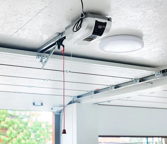 A ceiling-mounted garage door opener with a digital display and a red emergency pull cord, adjacent to a round ceiling light, conveys a modern, efficient setup.