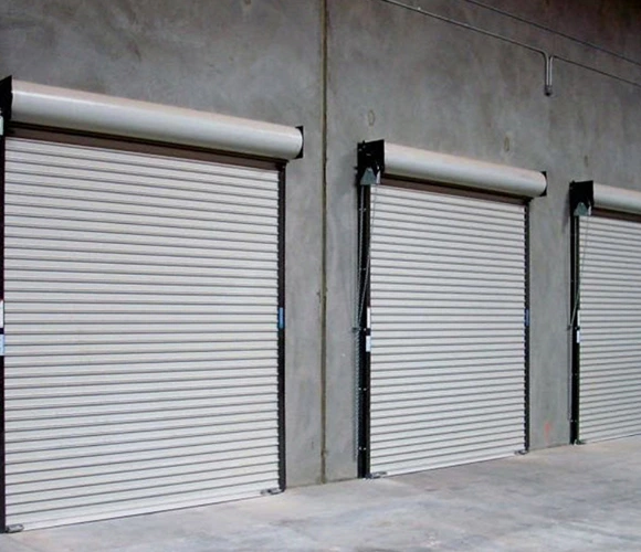 Three closed industrial roller doors on a concrete wall, evenly spaced in a warehouse setting. The tone is functional and neutral.